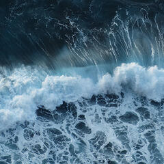 A photo of light and dark teal waves crashing against each other and making foam.